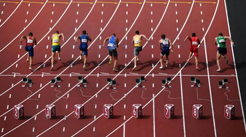 Track and field runners accelerating through a stadium turn